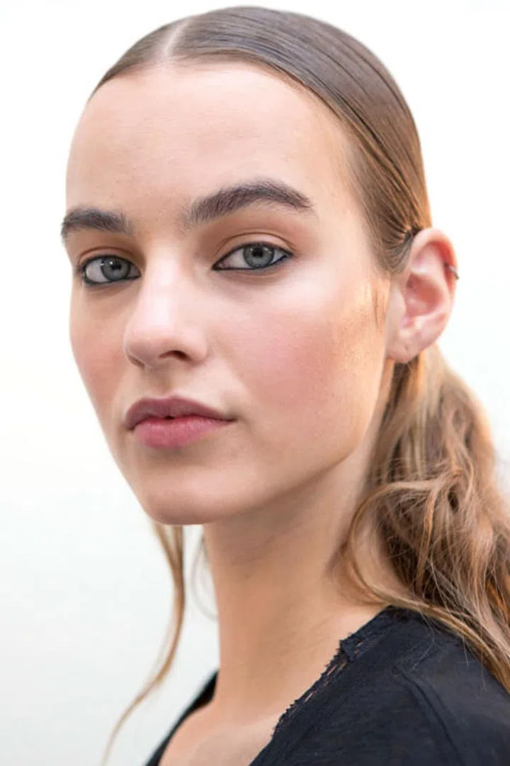 Makeup artist Sally Branka created the surfer girl beauty look at Thierry Mugler. After dabbing on concealer, Branka and her team brushed a powder bronzer all along the eyelids, along the lower lashline, and across both cheekbones and down the nose. A little blush was swirled on the cheeks. Then, a black kohl pencil was traced along both the top and bottom waterlines. Branka wanted it to feel like the Mugler surfer girl might have just gotten out of the water, drew on some black eyeliner, and went on her way. Before the models walked out, the makeup artists pressed the Clarins Blue Orchid face oil on the tops of the cheekbones and through the brows to give an unmistakable sheen (not shimmer) to the skin.