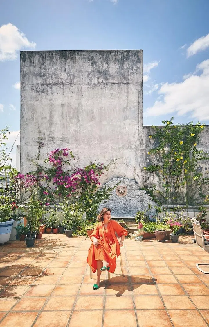 Sandra Cameron on her huge patio—the “hidden” gem
of her walk‐up apartment— seated on a Louis Ghost chair designed by Philippe Starck for Kartell, wearing her own Ulla Johnson dress and vintage YSL slides teamed with pretty bling. (Photo: Veronica Tay)