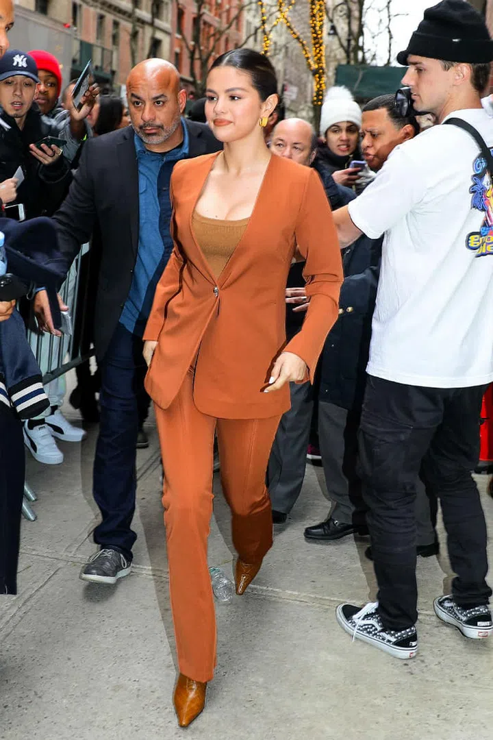 Selena Gomez wears a camel coloured suit from Gauge 81 with a brown top, Yuul Yie's  Gloria boots and the Ora Hoops from Jenny Bird.

Photo: Jose Perez / Getty