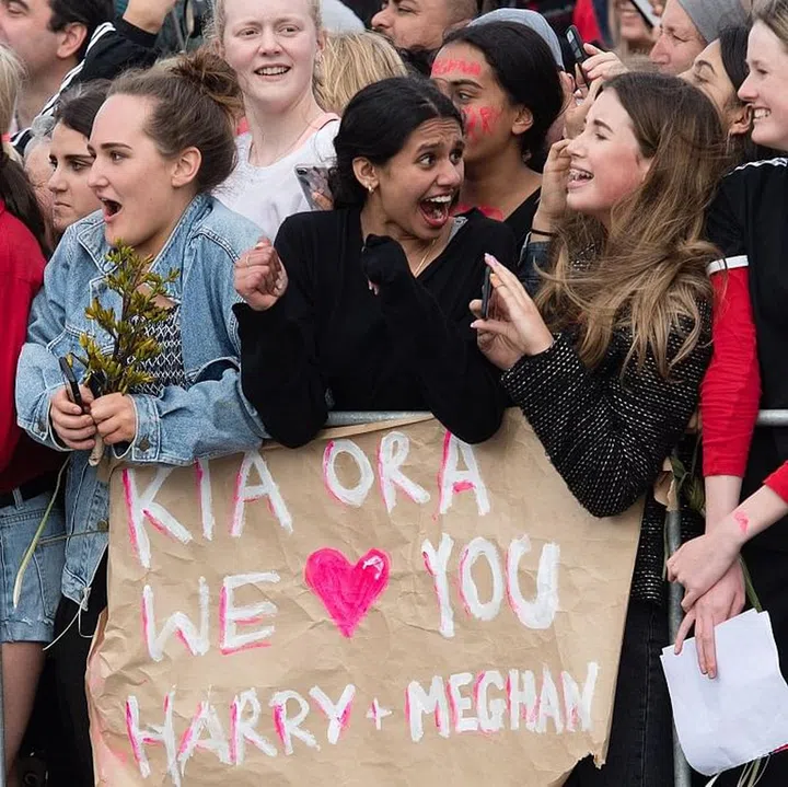 Fans excitedly hold signs for Meghan and Harry. Photo: Getty 