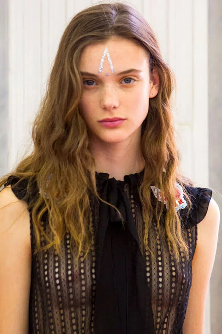 Glitter was used to create graphic tattoo shapes on the faces of models backstage at Giamba.