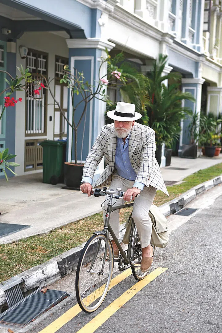 Cain looking fly while cycling in sharp tailoring and a Panama hat. (Photo: Bill Cain)