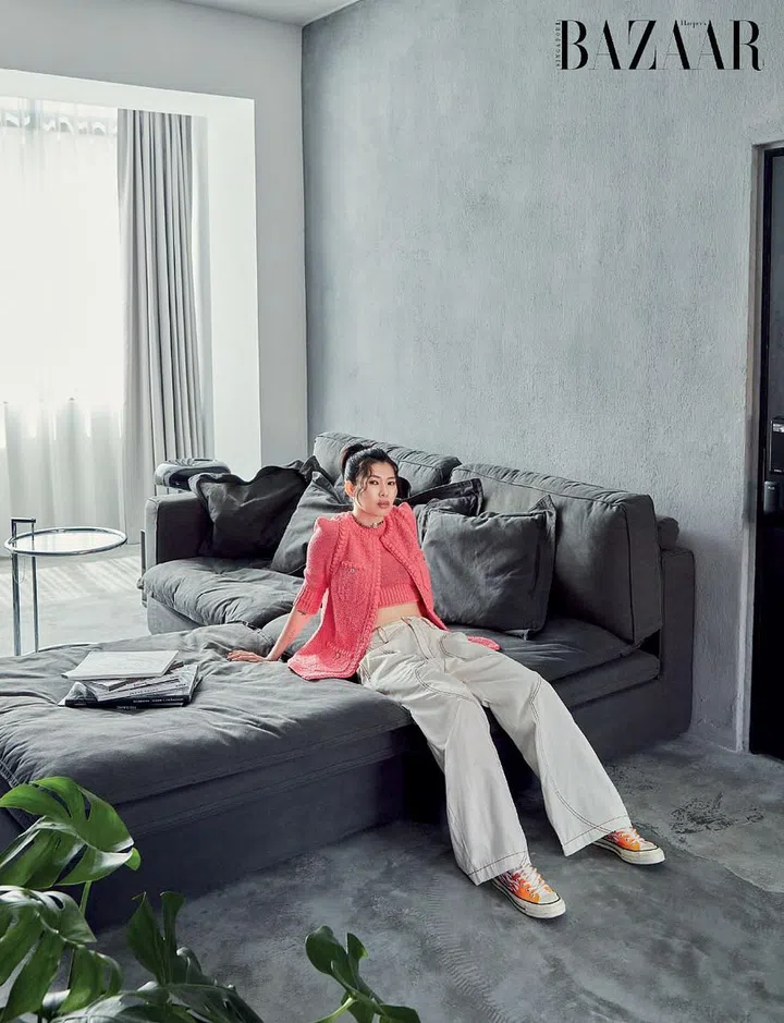 Nicole Wong, in a Chanel vest, top and choker worn with Comme des Garçons denim jeans and Converse sneakers, lounging on a Journey East sofa in her living room.