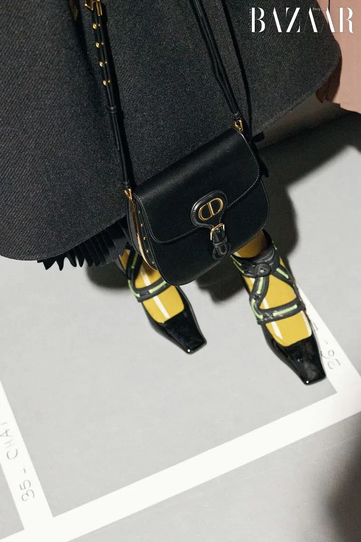 Double-face wool and cashmere coat; kid mohair skirt; black box calfskin Dior Bobby Frame bag; patent calfskin, neoprene and “Pied de Chèvre” fabric Dior 62-22 in collaboration with Roger Vivier pumps; cotton The Next Era high socks, Dior
