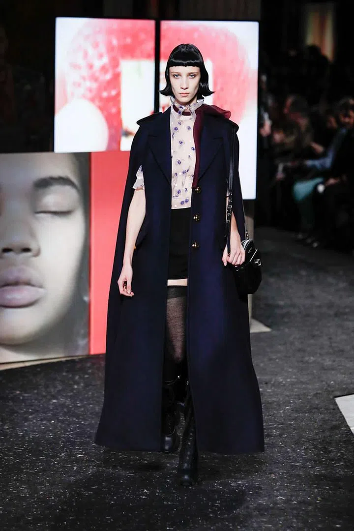 After a Prada showing in Milan that riffed on the ladylike shapes and tropes of Mid-century haute couture, Miuccia Prada skewed her latest Miu Miu collection in a much more girlish direction. On the runway were sheer skirts and blouses, short shorts, tiered dresses, ruffled necklines, cherry blossom prints and crystal mesh collars. The mood was definitely youthful but twee it was not.
This season’s Miu Miu girls are not fairytale princesses living in a fantasy world; instead, they are very much equipped for the realities of our current climate. On their feet were fierce lug-soled combat boots; on their shoulders, sturdy wool capes whooshing almost all the way to the floor in a way that spoke of protection. Alternatively, Prada draped them in granddad cardigans, or a wide
array of camouflage hoodies, coats and faux furs. Satin pumps, strappy sandals
and glitter heels added fashion magic to the militant mix.