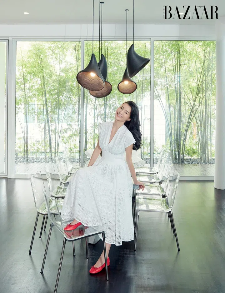 Wu in her sleek dining space against a backdrop of bamboo plants. She wears a Tory Burch dress and her own Repetto pumps. Photo: Gan