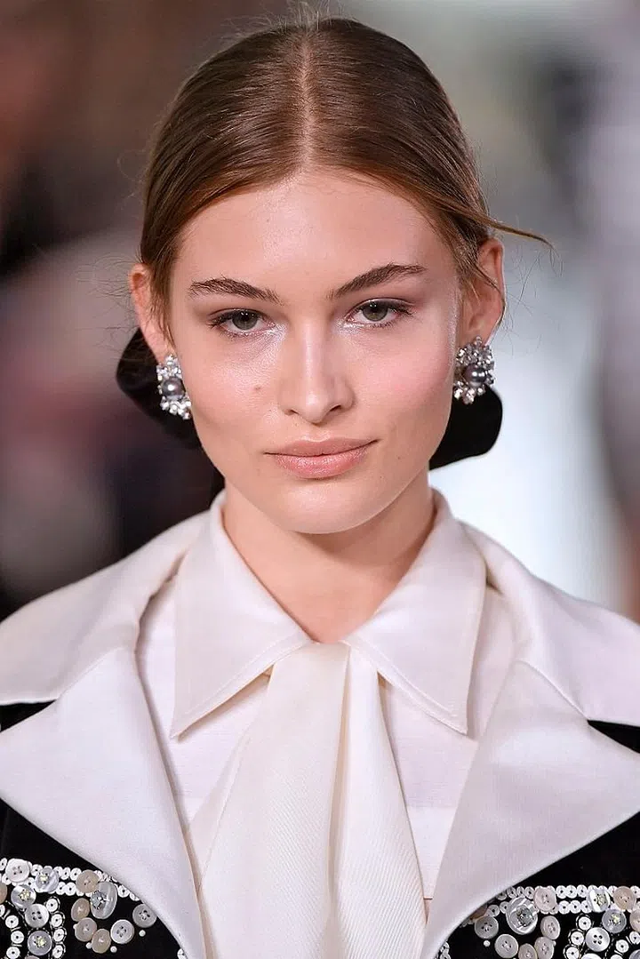 Youthful sophistication is epitomized by Tory Burch's classic beauty look. Models had luminous, glowing skin with a slight flush of pale pink on the apples. Brows are lightly filled in and then brushed up for a textured effect. Eyes are illuminated with silver eyeshadow while the lips are a gorgeous peachy nude. We can't forget the effortless low-pony that all the models had, with a chic center-parting. We are ready to take this look right off the runway and into real life. Photo: Getty 