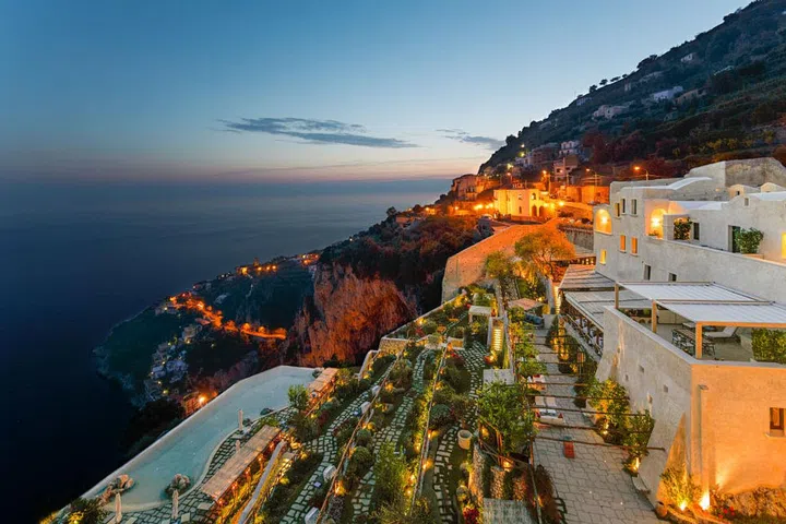 A ruin of a 17th-century convent was transformed into a 20-room luxury resort, and is perched cliffside with stunning panoramic views of the Amalfi Coastline and Mediterranean Sea below. The infinity-edged pool is dramatically situated, appearin to hang over the edge of the cliff. 