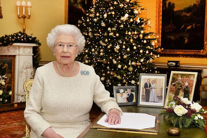 The Queen is like every other mom and grandmother: Extremely proud of her family, as evident by the family photos on her desk. We also couldn't help but notice how her ensemble coordinates with the ivory flowers and tree ornaments.