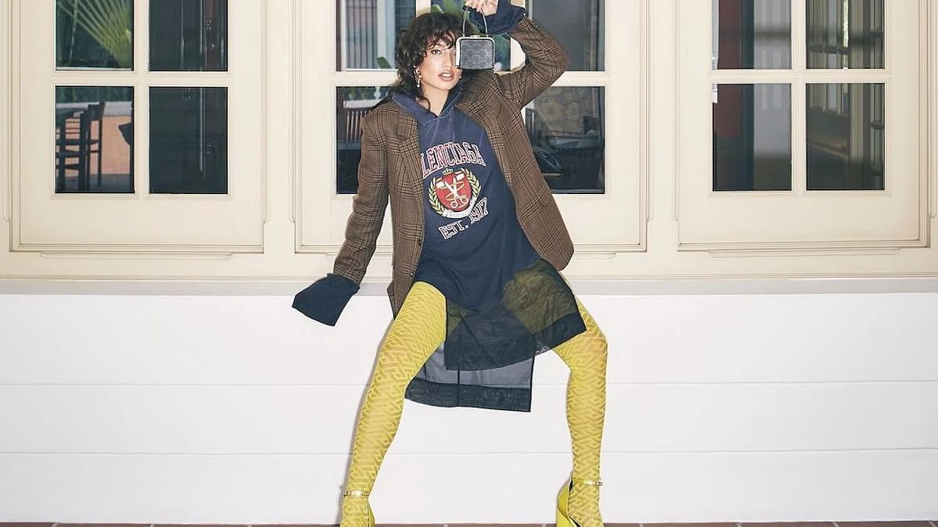 Hoodie, by Balenciaga. Blazer; bag; both by CELINE by Hedi Slimane. Skirt, by H&M. Tights; heels, both by Versace. Ring, by Swarovski. Earrings, by Saint Laurent by Anthony Vaccarello. (Photo: Veronica Tay)