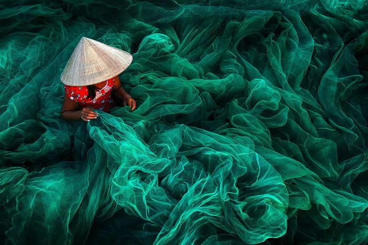 "In a small village in southern Vietnam near Phan Rang, a woman wearing a typical cone hat is creating a fishing net in their traditional manner. The manufacturing of handmade nets is still a typical Vietnamese activity for women which they carry on while their husbands are out fishing." –Danny Yen Sin Wong