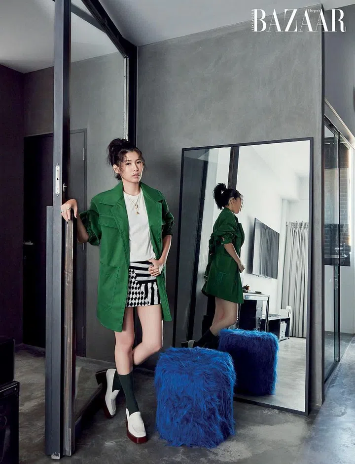 Wong in her minimalist master bedroom wearing a Tod’s coat and loafers, Rick Owens tee and Dolce&Gabbana skirt teamed with Prada earrings as well as her own necklaces and rings.