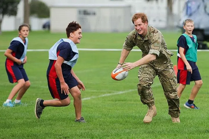 Playing a game of touch rugby with children during a visit to Linton Military Camp in 2015. Photo: Getty