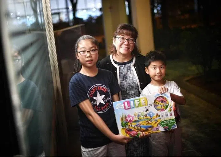 Ms Angeline Wee (centre) teaches her children Janelle (left) and Noel Foo financial literacy through board games like Life. PHOTO: ARIFFIN JAMAR/THE STRAITS TIMES