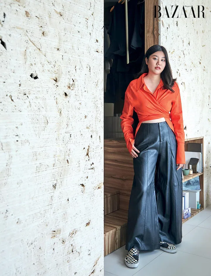 Standing in her bedroom, Tan is in a top by Gauge81 via Net-a-Porter, and her own leather trousers and Vans sneakers.