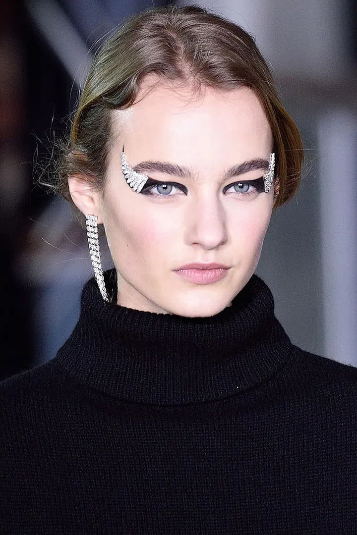 While the majority of models walked the runway with Parisian au natural makeup, three were given crystal cat-eyes that Tom Pecheux described as looking like "Beauty & the Beast." To create them, he drew wings across the lids and out with shiny black liner, pressed makeup adhesive at the outer corners and "glued" down deconstructed pieces of the earrings in the collection. The final step, to keep the crystals from feeling too overpowering, involved tracing the liner along the lower lashes and up around the edge of the embellishment for seamless fluidity.