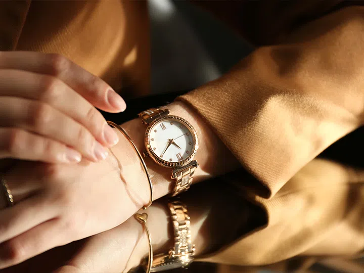 woman in suit wearing gold luxury watch