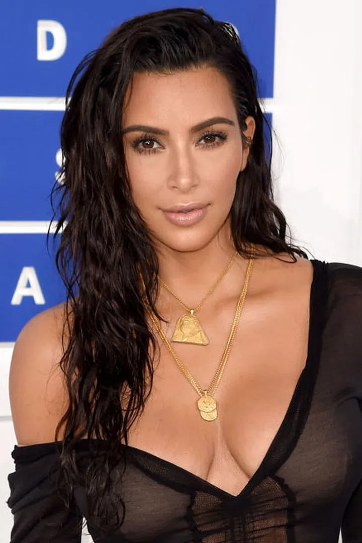Kardashian looks decidedly back-from-the-beach with a healthy glow, shiny lips, and wet waves. 