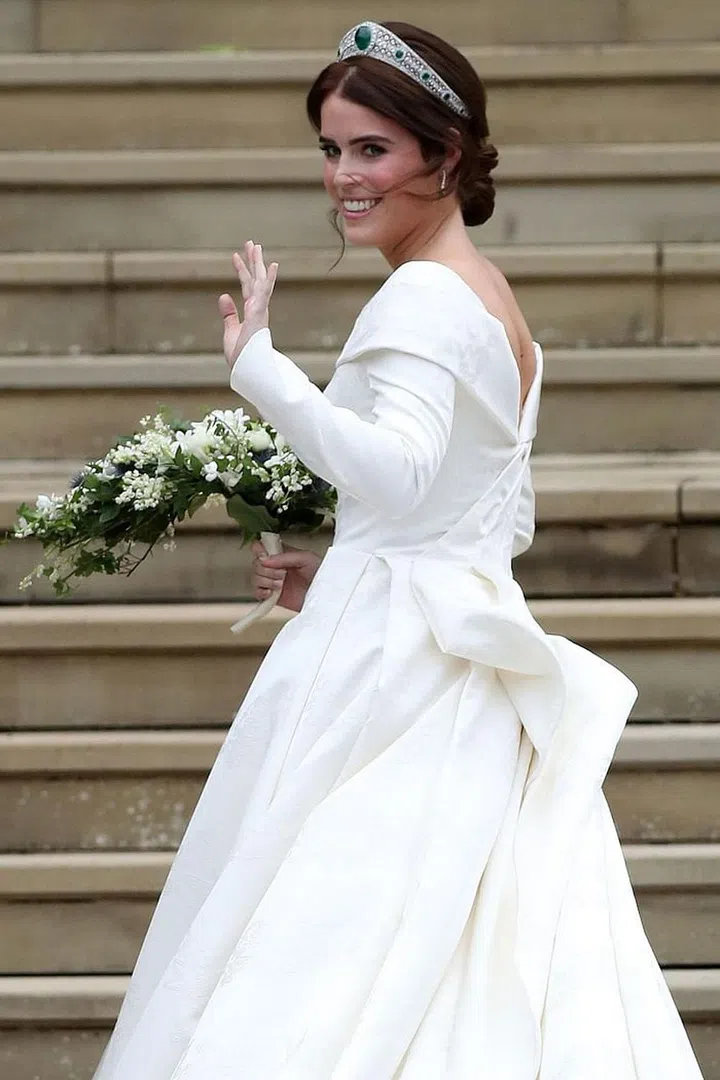 The bride waves to the crowd outside of the chapel.