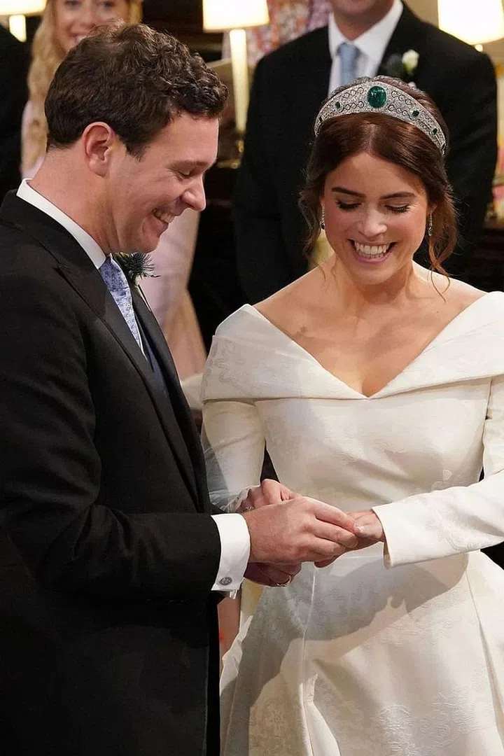 The bride and groom laugh lovingly while exchanging rings.