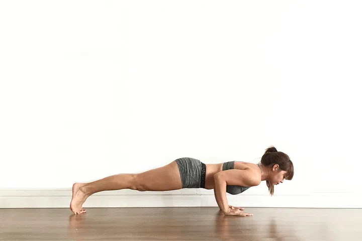 The Chaturanga is one of the most fundamental movements in Yoga. It is a pushup with elbows grazing the sides of the ribs held at 90 degrees. Practitioners looking to build strength can start off by placing their knees on the mat and having their body kept in a plank position, whereas Intermediate to Advanced practitioners can experiment with knees off the mat and lengthening their time in Chaturanga by a few more breaths.