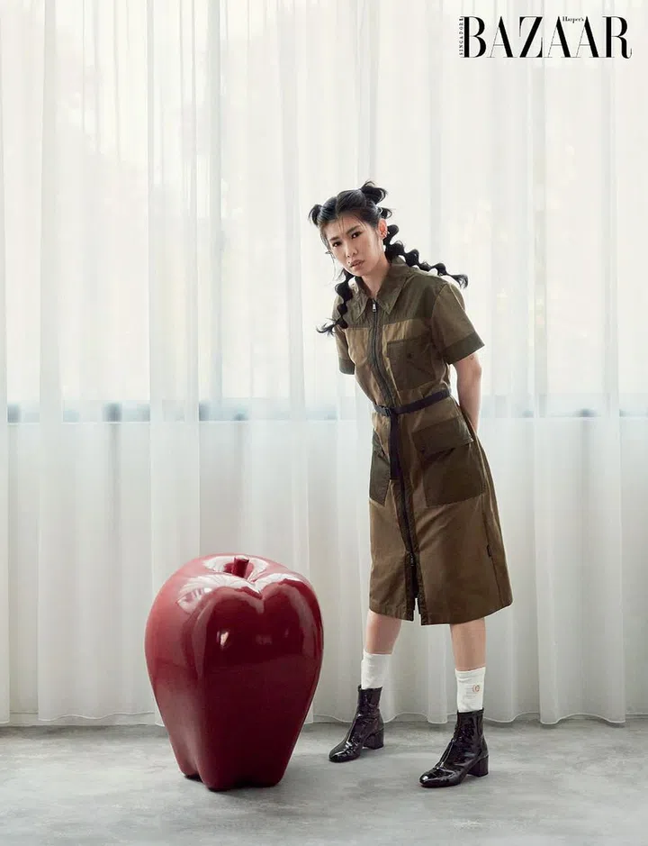 Wong, outfitted in a Moncler dress and Chanel sock‑boots, posing with an apple prop meant for a window display—one of the many quirky décor items that dot her home. 