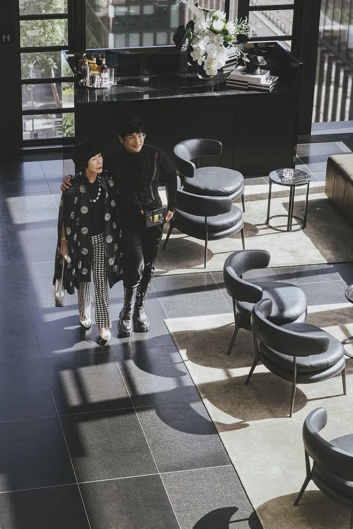 Goh in a H&M Studio top, Prada trousers and boots and a Louis Vuitton bag, with Ooi, in a H&M Studio cape, ZARA top and trousers, and Roger Vivier bag and shoes, in the sun‐bathed sky lobby of A by Adina Sydney. (Photo: Arvin Prem Kumar)