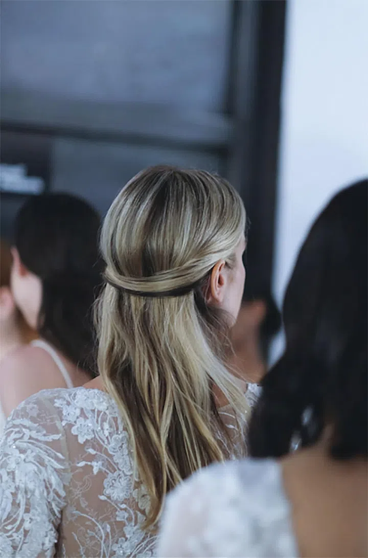 The half-up bridal hairstyle got a cool makeover this bridal season. Instead of pulling hair into a voluminous half-up section, just the face-framing layers were pulled back and laid flat with a few bobby pins.