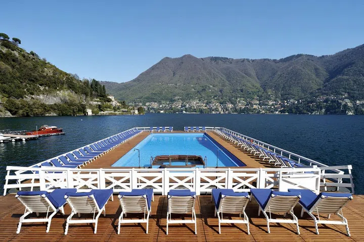 In Cernobbio, Italy, Villa D'Este, a member of the Leading Hotels of the World, occupies an enviable spot on Lake Como, amid 25 acres of luxuriously landscaped park. Surrounded by a wooden deck built into a pontoon that floats on the 28-mile lake, the hotel's pool has breathtaking views of mountains and Italy's third largest lake. The property is divided between two historic mansions, one dating from the 16th century, and the other built for a queen of England.