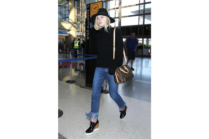 Elle Fanning keeps the focus on her fringe 3x1 jeans, styling them with platform wedges and an oversize knit : Photo: Getty