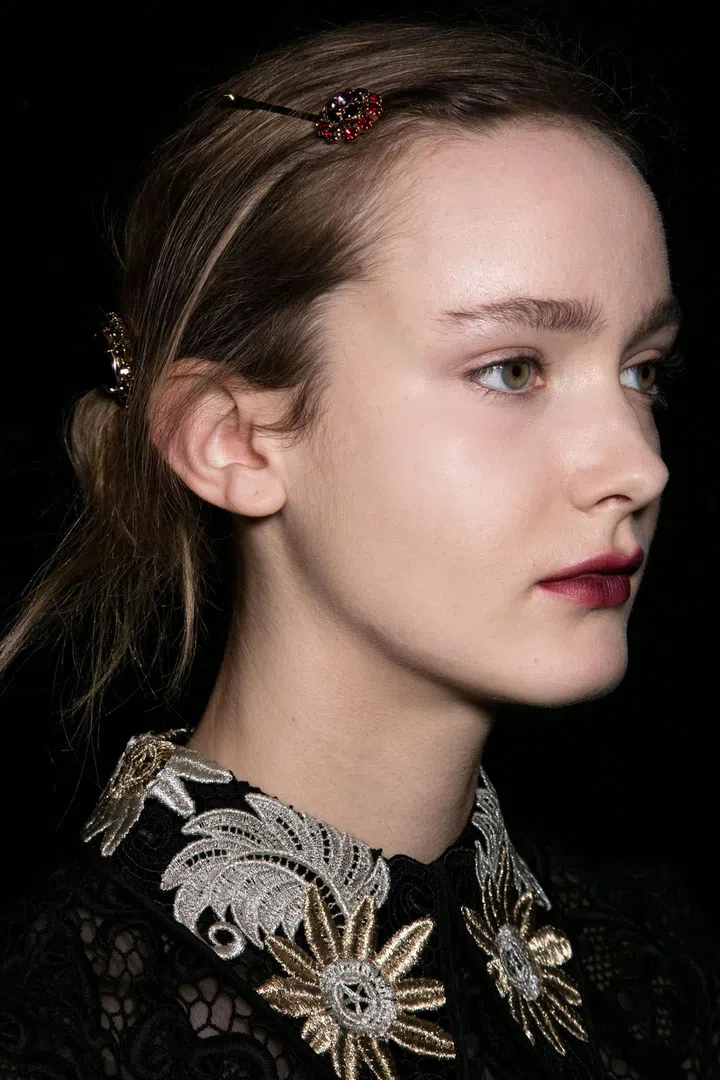For a modern nod to the '30s, Anthony Turner pulled the hair into a low ponytail, rolled it in toward the nape of the neck and held it in place with jeweled bobby pins, while Val Garland painted on Black Dahlia-inspired lips using NARS Velvet Matte Lip Pencil in Train Bleu and Mysterious Red.