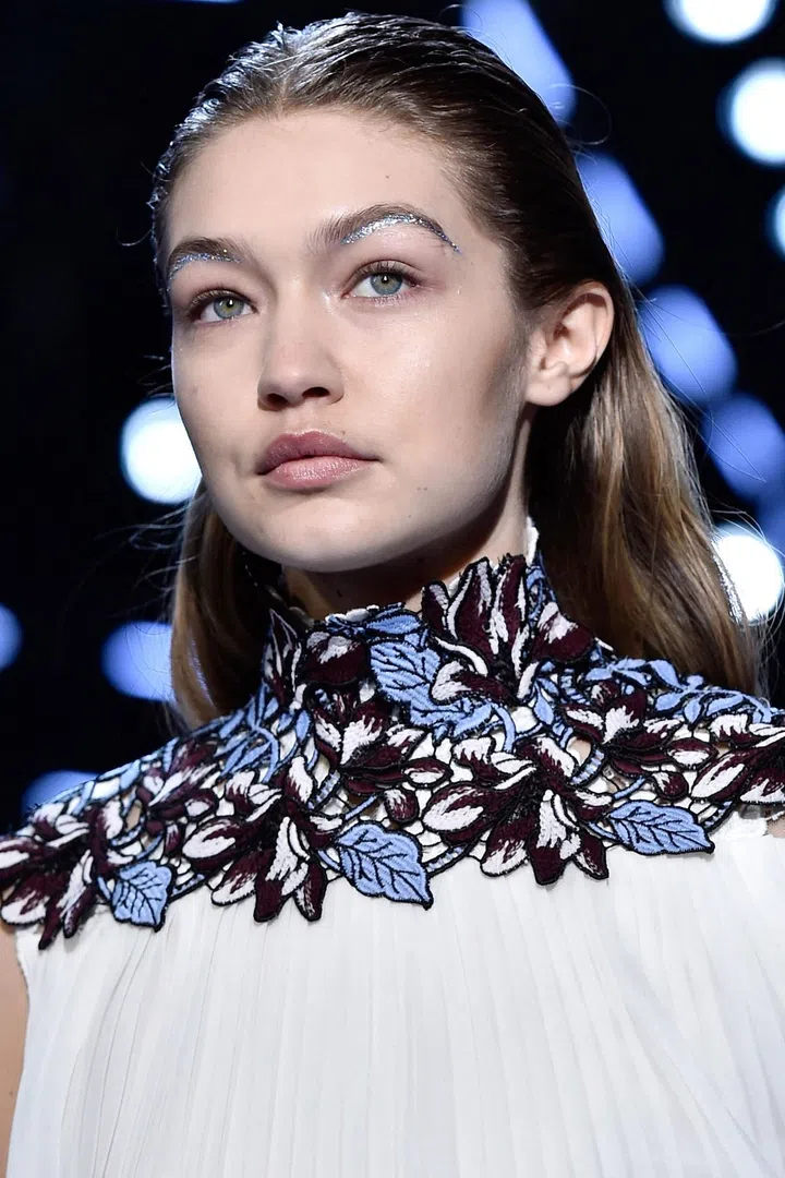 "Giambattista always likes to feel like his girl has just come out of the shower and thrown on her dress," said makeup artist Val Garland backstage. "Here, it's all about the celebration of women, which I interpret as, every woman should have a silver lining in her life." Hence, the holographic flashes of sparkle, visible only as the models turned their heads just so on the runway. Garland started by mixing pigment with Mixing Medium to create a liner, which she drew along either the lash line or just under the brow bone. Once that set, she dabbed more clear Mixing Medium over it to act as an adhesive, then applied the ultra-reflective glitter on top.