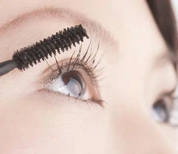 Woman putting on mascara