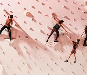 corp extremes acrobats performing routine on a rock wall