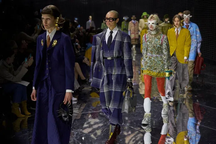 A hundred thousand flashing lights served as backdrop, one moment illuminating the clothes with extreme clarity, the next leaving the audience almost blinded. It was a fitting metaphor for the idea Alessandro Michele decided to explore—one of identity, what we choose to conceal from the world, and what we reveal. Hence the motif of masks, and Michele revelled in all the connotations of kink, horror and celebration associated with this device of disguise. On one hand, there were spiked collars and harnesses; on the other, gold-plated earpieces, face shields and breastplates. As for the clothes, it was a still a maximalist affair but there was
also a newer sense of restraint. In what has become a key trend, tailoring was a highlight. Michele made his stand out via
inventive experiments in shape and proportion, with extra-wide legs cinched at the cuffs for a ballooning effect, and fat ties tucked into ultra-high waists.