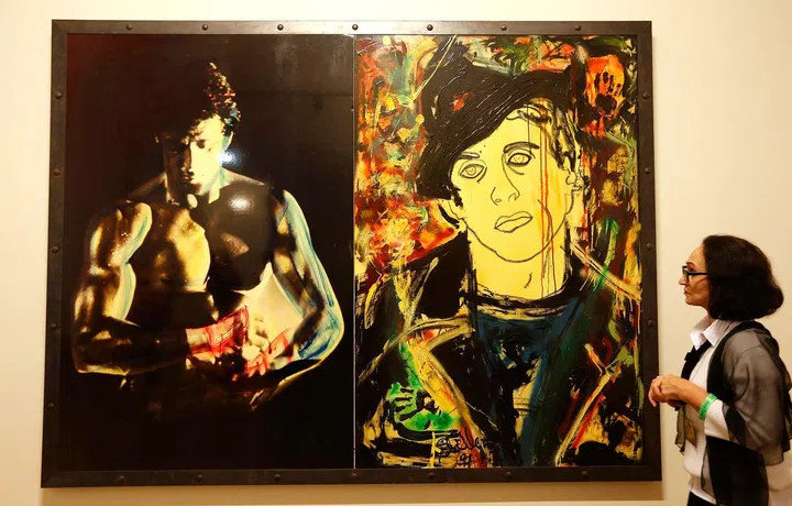 A woman looks at the painting "The Arena" at the art exhibition titled "Sylvester Stallone. Painting. From 1975 Until Today",  at the Russian Museum in St. Petersburg October 27, 2013. The exhibition by Sylvester Stallone, who has worked on his pieces for more than 30 years, consists of 36 paintings, according to local media.     REUTERS/Alexander Demianchuk   (RUSSIA - Tags: SOCIETY ENTERTAINMENT)