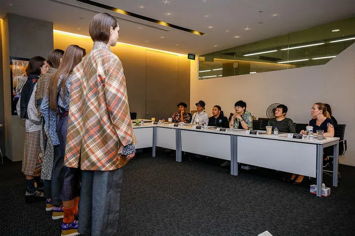 The judges looking at the first finalist's collection. 