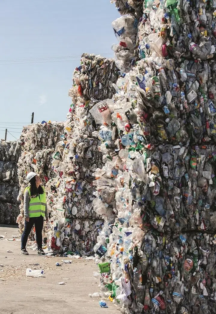 Sorted waste bundles tower above Miranda Wang at California’s GreenWaste Recovery facility.
