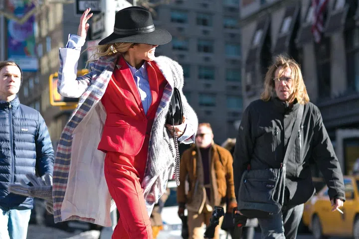 A checked overcoat with hints of red adds harmony to a red suit 