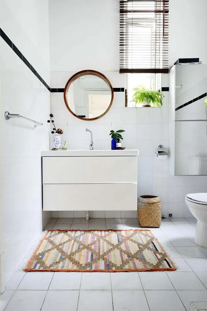 Black trimming and graphic rug add visual interests to this all-white bathroom. (Photo: Carli Teteris, courtesy of Grounded)
