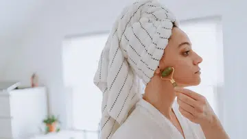 Woman using jade roller on her face at home
