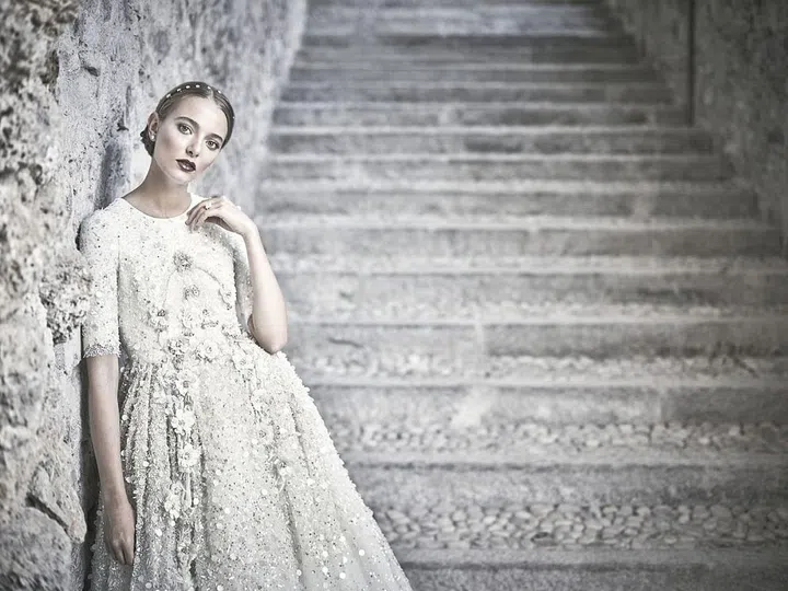 Remember royal wedding mania? How could we forget when the Duchess of Cambridge's Alexander McQueen by Sarah Burton gown gave made it chic for brides to consider covering up once again (even if they weren't dressing for the Abbey). Then, the rise of the super sexy bride emerged, with head-to-toe illusion gowns, open backs, plunging-V necklines and sheer skirts in tow. Gowns that leave little to the imagination are a feat of fashion engineering–but they can leave little room for actual design. Chana Marelus, based in Israel's Bnei Brak, an Ultra-Orthodox Jewish community just outside of Tel Aviv, answered the call of her conservative clientele: those with a religious, customary need to cover up–but wanting to do so with the style and taste level of the Paris runways. In her bridal and evening range, sleeves and high necklines are a given; so are jaw-dropping beadwork, stunning long trains and impressive texture plays. With the silhouette options slightly limited, Marelus experiments with color, beading, texture and detail–expect a perfect fit, dramatic capes and skirts and details that hearken to Haute Couture.