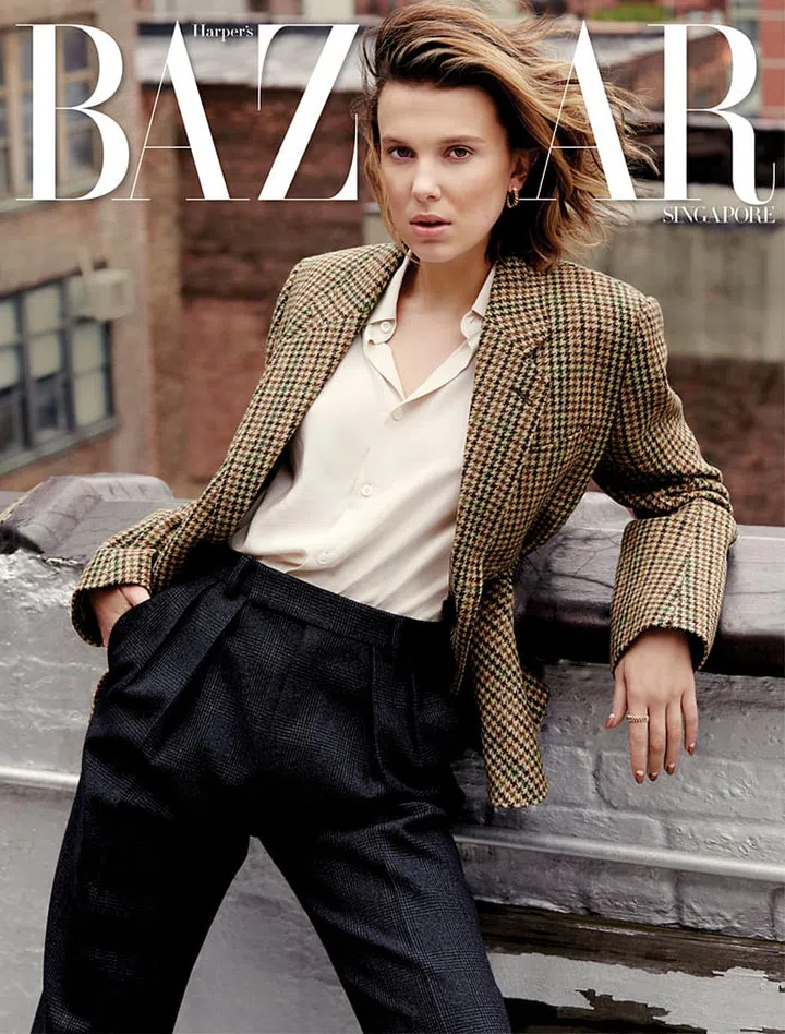 Millie Bobby Brown wears wool jacket; silk blouse; wool pants, CELINE by Hedi Slimane. Gold Clash de Cartier earrings, gold Clash de Cartier ring, Cartier. Photo: Yu Tsai