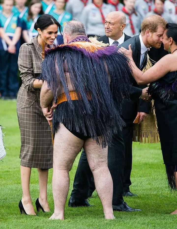 Harry performs a hongi, which is a traditional Mãori greeting. Meghan is wearing a Karen Walker Banks plaid trench, with her favorite Sarah Flint pumps. Photo: Getty 