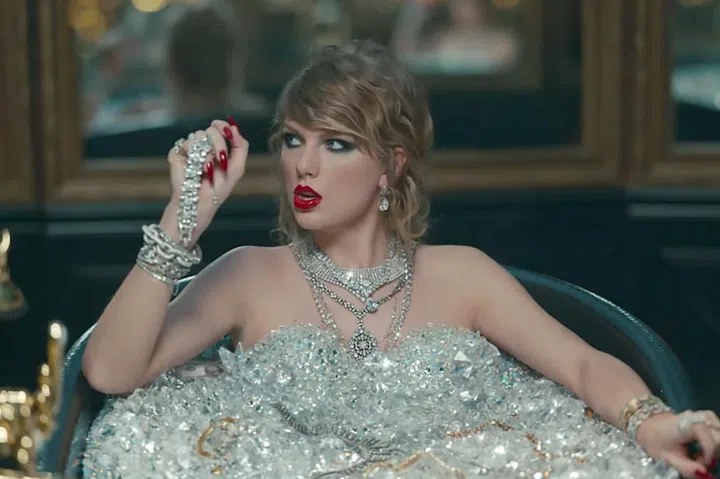 While taking the world's most-painful bath to wash the dead off of her, Taylor rocks a super-smudgy cat eye, a loosely curled chignon, and some vinyl red lips to match her dangerously sharp nails. 
