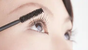 Woman putting on mascara