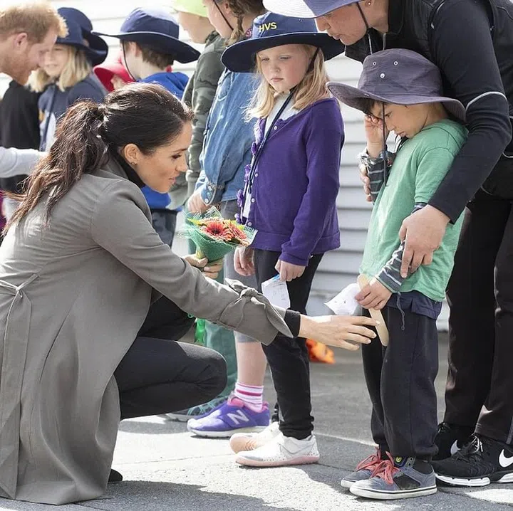 Meghan comforts a crying boy who is waiting to meet her. Meghan is wearing Varuka lace-up boots by Stuart Weitzman and a coat by Club Monaco. Photo: Getty 
