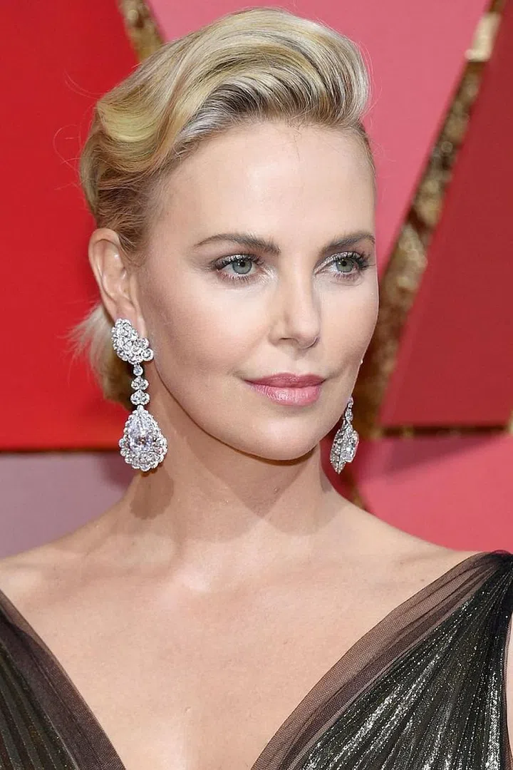 Red carpet bombshell Charlize Theron balances a sleek ponytail with a voluminous wave across her crown. Photo: Getty
