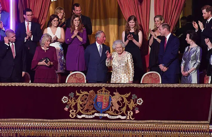 The Queen waves at the crowd as the royal family looks on.
