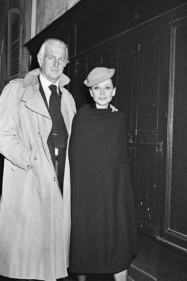 At a restaurant in Paris, Audrey wears a hat and caped coat.